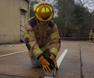 Fire Academy student rolling a hose during training