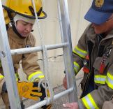 Fire academy student tying knot on ladder 